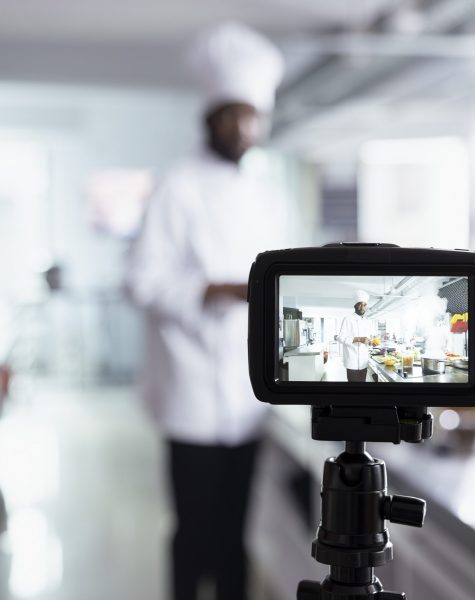 African american chef teaches his audience cooking skills on a video, explaining preparation methods and plating techniques. Expert hosting virtual classroom for online culinary training.